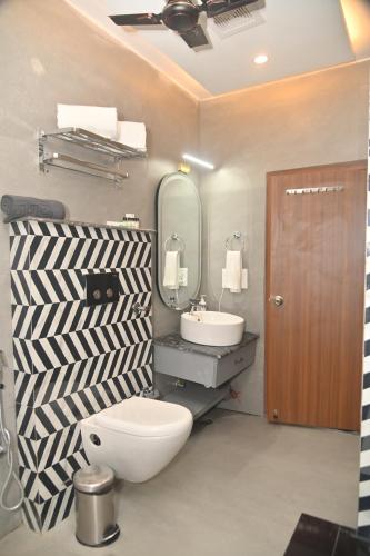 a bathroom with a toilet and a sink and a mirror at Aarush Hotel & Resort in Haldwāni