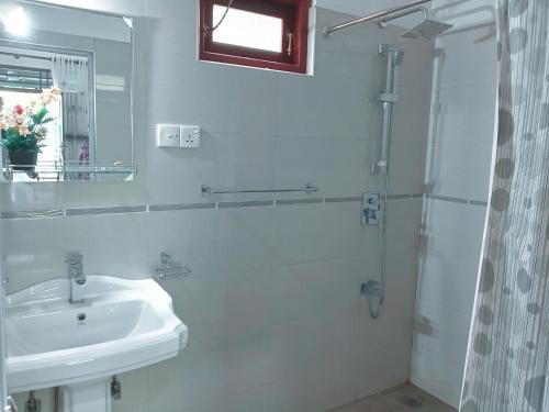 a white bathroom with a sink and a shower at Ceylonika Rest in Bentota