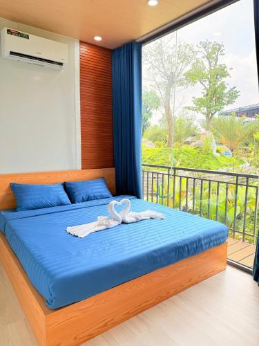 a bedroom with a bed with blue sheets and a window at Uniton Zen Garden in Ấp Bến Cầu