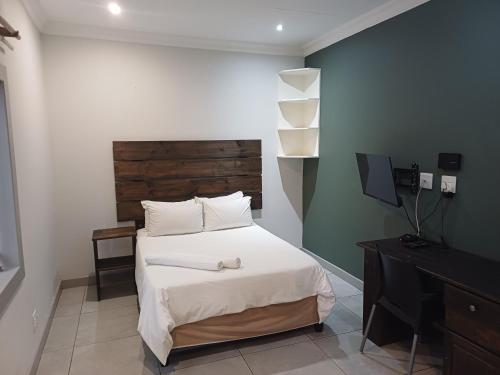 a bedroom with a bed with a wooden headboard and a desk at Triple9 Hatfield Guesthouse in Pretoria