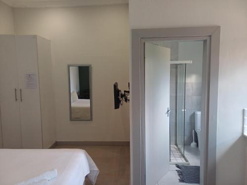 a bedroom with a bed and a bathroom with a shower at Triple9 Hatfield Guesthouse in Pretoria