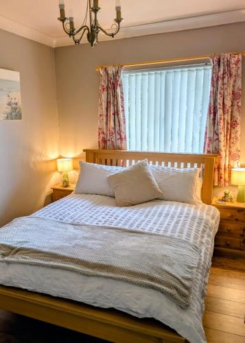a bedroom with a bed and a window with curtains at White Pebbles Appartment in Ilfracombe