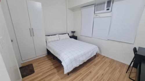 a small white bedroom with a bed and a window at Cozy Studio Long Stays Welcome in Biñan