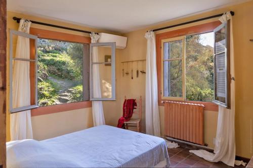 a bedroom with a bed and two windows at Villa MARION bord de mer in Pino