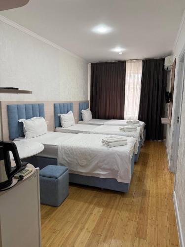 a hotel room with two beds and a chair at Avenue Hotel Tashkent in Tashkent