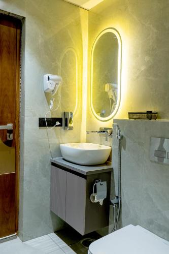 a bathroom with a sink and a toilet with two windows at Hotel Panipat Prime in Pānīpat