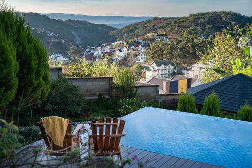a house with a swimming pool and two chairs at Zenora Hillside Garden in Da Lat