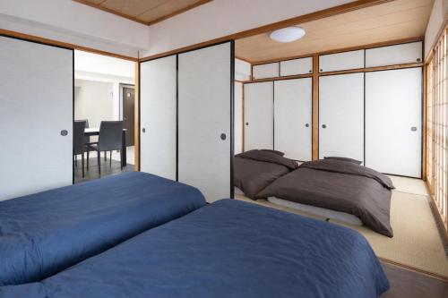 two beds in a bedroom with sliding glass doors at マンションメゾンV206 maisonV206 in Gifu