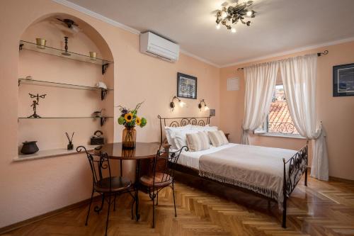a bedroom with a bed and a table and a window at Antaeus Old Town Residence in Dubrovnik