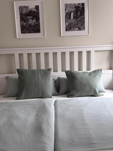 a white bed with two pillows and two pictures on the wall at Heimelige Wohnung Bei der Stoffschmiede in Schutterwald