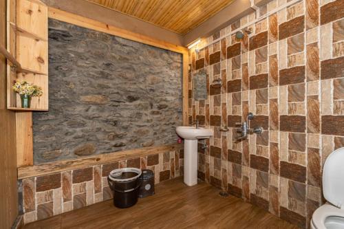 a bathroom with a sink and a stone wall at NotOnMap - H2O House in Chamba