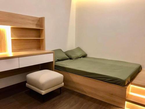 a small bedroom with a bed and a stool at Căn hộ 2PN THE EMERALD GOLF VIEW in Thuan An
