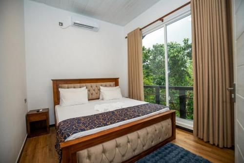 a bedroom with a bed and a large window at Visbury Villa in Gangaboda