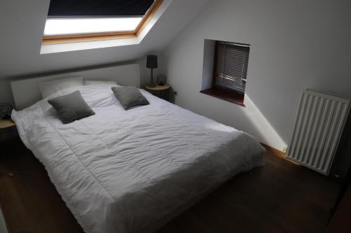a bedroom with a large white bed with a window at Pause-toit, Le gîte de Mozet. in Gesves