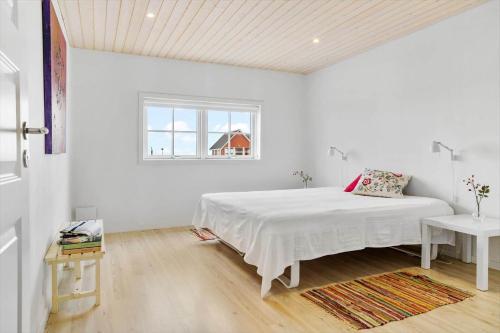 a white bedroom with a bed and a window at 20124-Samso-Maarup-Havn-3 in Nordby
