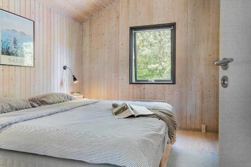 a bedroom with a large bed in a wooden wall at 20220-Samso-Rosenvej-25 in Tanderup