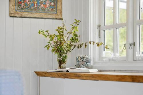 a table with a book and a vase with a plant at 20132-Samso-Skovvejen-7 in Nordby