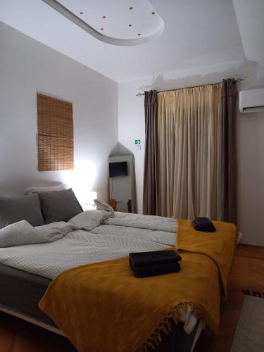 a bedroom with a large bed with a yellow blanket on it at B&B Baš Baštica in Kladovo