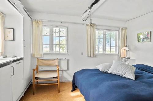 a bedroom with a blue bed and a chair at 20509-Samso-Egevej-13 in Onsbjerg