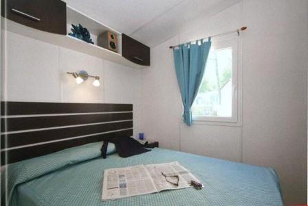 a bedroom with a bed with a newspaper on it at Flower Camping Le Pont du Tarn in Florac