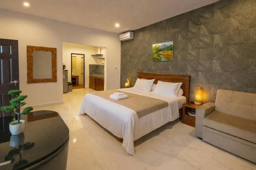 a bedroom with a bed and a couch and a chair at Serendipity Bali in Sanur
