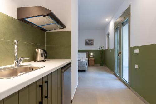 a kitchen with green walls and a sink and a hallway at Anopoli Rooms in Sinoikismós Kámbos