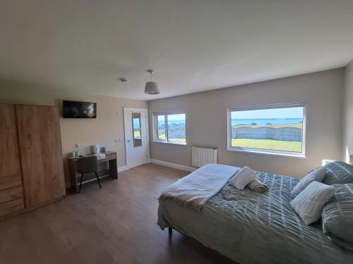 a bedroom with a bed and a desk and a window at Cliff Top Accommodation in Spanish Point