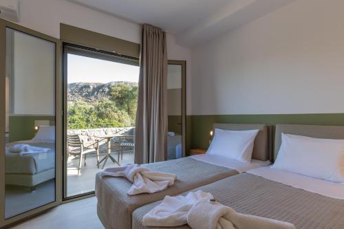 a hotel room with two beds and a balcony at Anopoli Rooms in Sinoikismós Kámbos