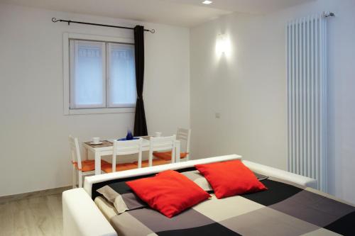 a bedroom with a bed with red pillows and a table at Ca di baragett in Mandello del Lario