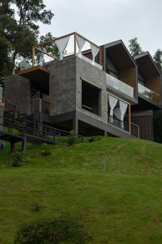 a building on top of a hill with a grass field at BaanTataChiangmai in Ban Pong Khai Tai