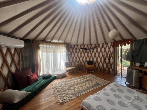 a room with a bed and a couch in a yurt at Meek Yurt in Yodefat