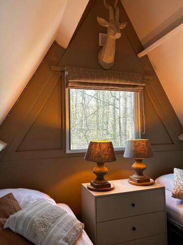 ein Dachgeschoss-Schlafzimmer mit zwei Lampen auf einem Nachttisch in der Unterkunft Chalet Woods in Durbuy
