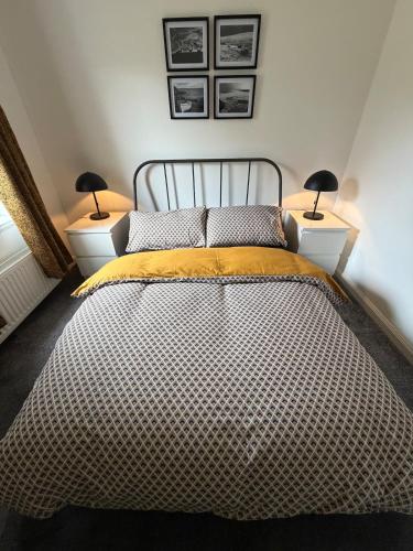 a bedroom with a bed with two lamps on either side at Heatherlea Cottage in Skigersta