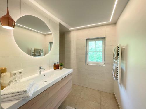 a white bathroom with a sink and a mirror at Hotel Garni Buchinger in St. Wolfgang