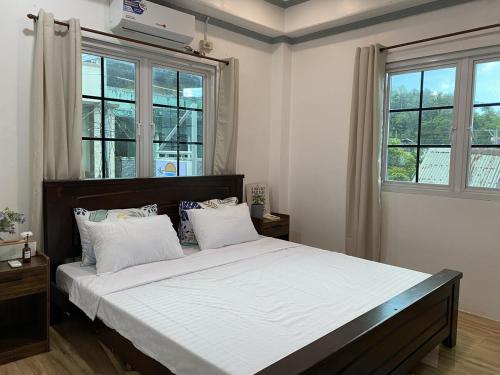 a bedroom with a large bed with white sheets and windows at Beachfront Sunset Getaway in Allen