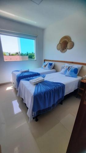 two beds in a room with a window at La casa de Luna in Guaibim