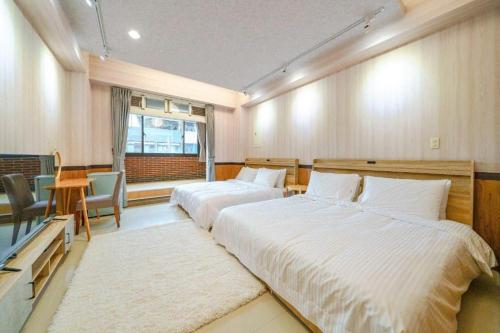 a bedroom with two beds and a table and a window at 湯韻溫泉 in Jiaoxi