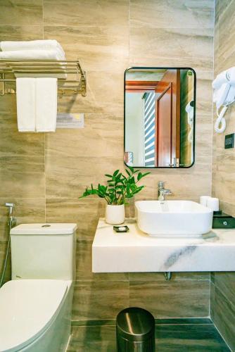 a bathroom with a sink and a mirror and a toilet at Thời đại Hotel in Thanh Hóa