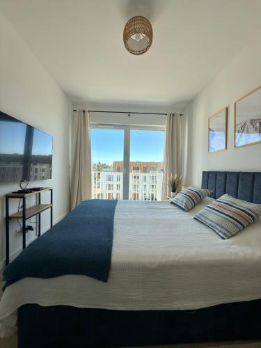 a bedroom with a large bed with a large window at Let's Sea Positive Vibe apartment in Gąski