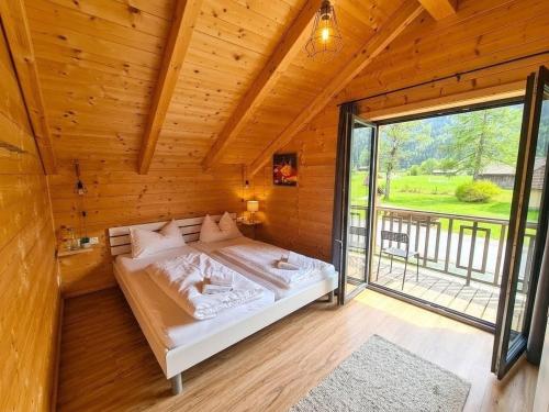 a bed in a wooden room with a large window at Chalet Rattendorf 139 in Rattendorf