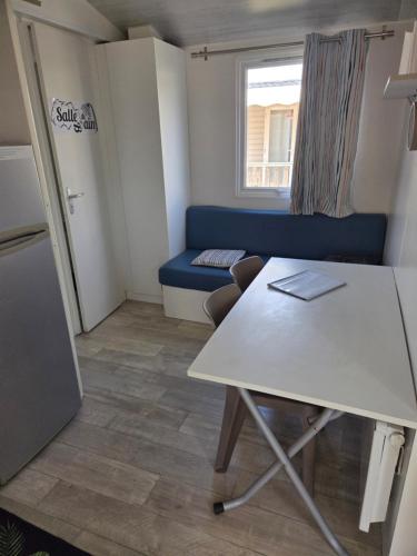a small room with a table and a blue couch at FMLODGE la cabane du soleil au sable du midi in Sérignan