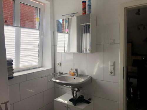 ein weißes Badezimmer mit Waschbecken und Fenster in der Unterkunft Rote Abendsonne in Ahaus
