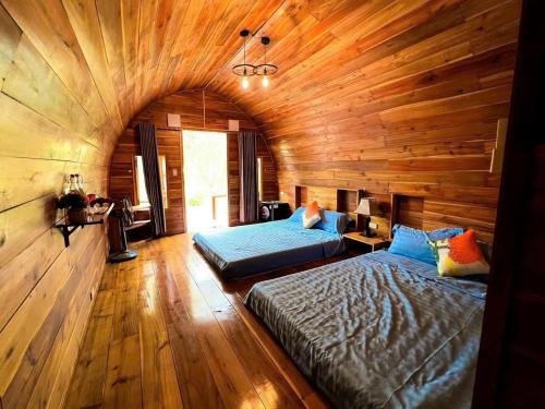 a bedroom with two beds and a wooden ceiling at Coto Queen in Nam Cap