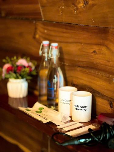 a table with two coffee mugs and bottles on it at Coto Queen in Nam Cap