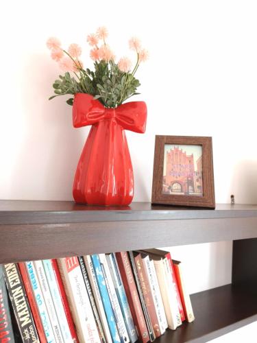 a red vase sitting on a shelf with books at STARE MIASTO in Olsztyn