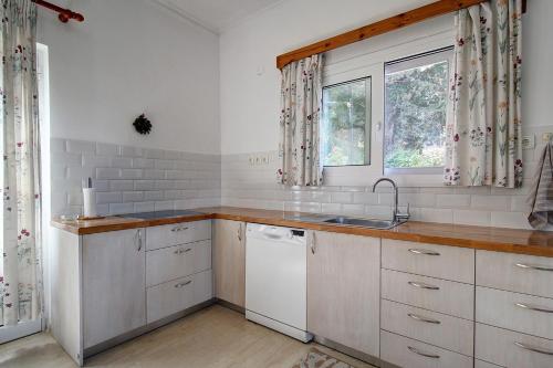 a kitchen with white cabinets and a sink and a window at Amethyst - holiday apartment in Likotinaréa