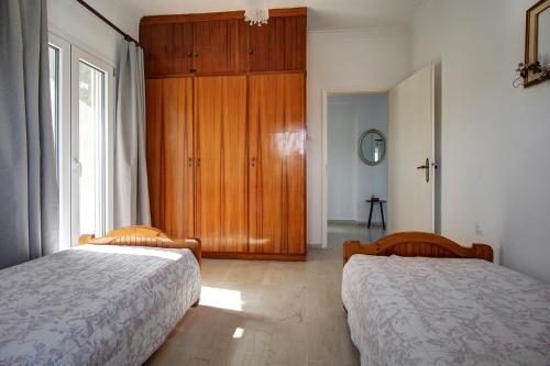 a bedroom with two beds and a wooden cabinet at Amethyst - holiday apartment in Likotinaréa