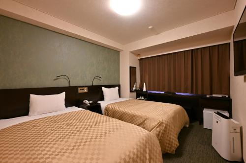 a hotel room with two beds and a window at Hotel nanvan浜名湖 in Kosai