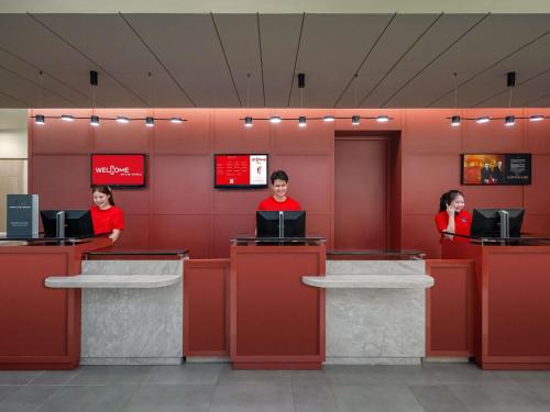 a couple of people sitting at a counter in a lobby at ibis Bangkok Siam in Bangkok