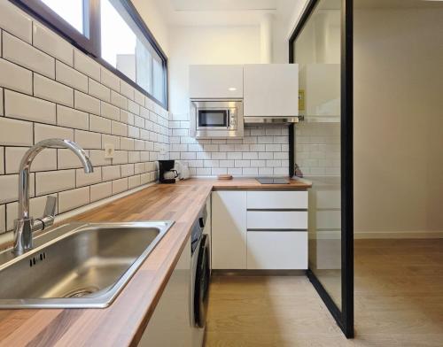 a kitchen with a sink and a microwave at Bilbao ROOMS & KITCHEN Zabalburu in Bilbao